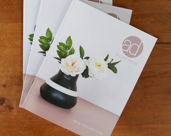 A stack of Accent Decor wholesale decor catalogs atop a table.