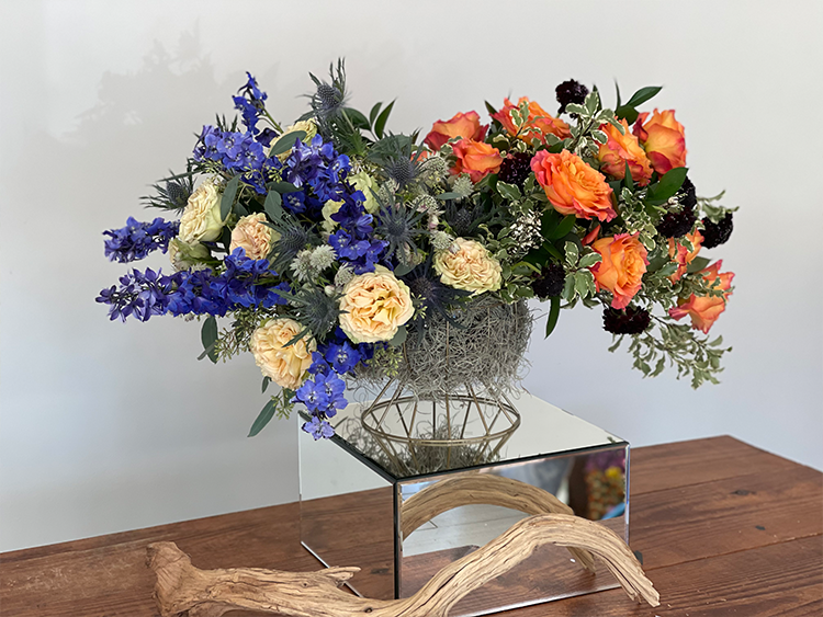 A lush and colorful floral arrangement, styled in Accent Decor's Cage Compote Bowl, atop a wooden table.