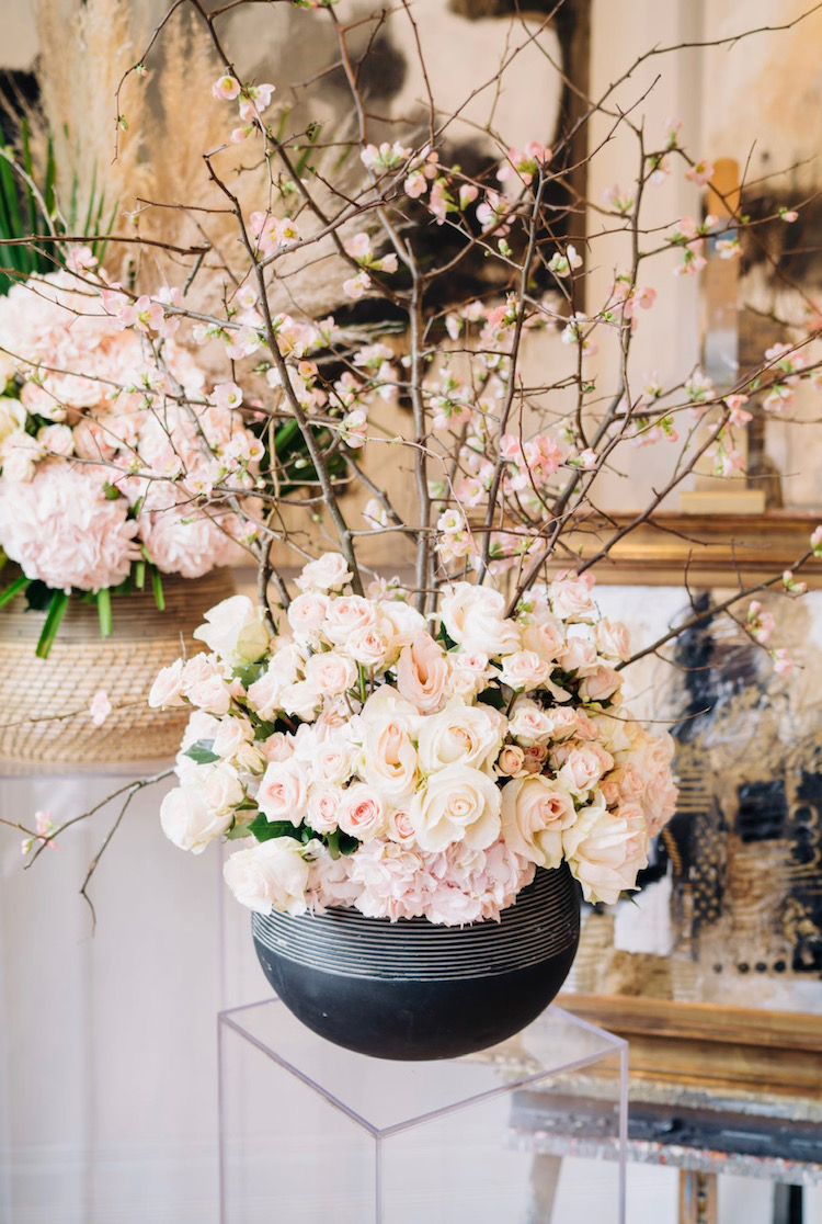 A lush floral arrangement contained in the Revolution Planter from Accent Decor atop a lucite pedestal.