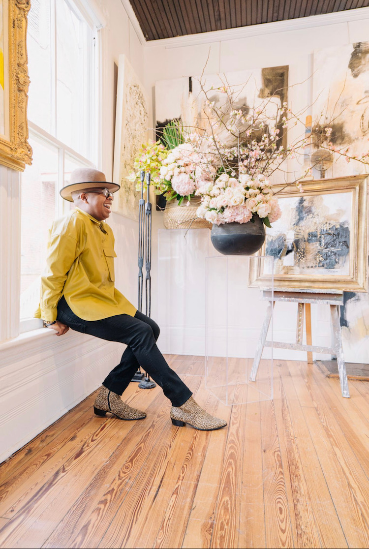 Canaan Marshall of Canaan Marshall Designs posing in a room outfitted with art and florals.