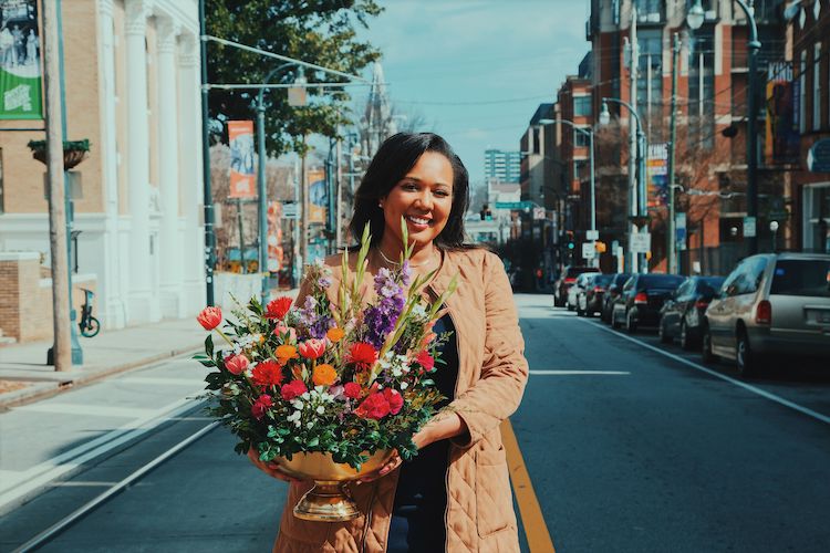 A woman holding a lush and colorful floral arrangement at Auburn Avenue in Atlanta, GA.