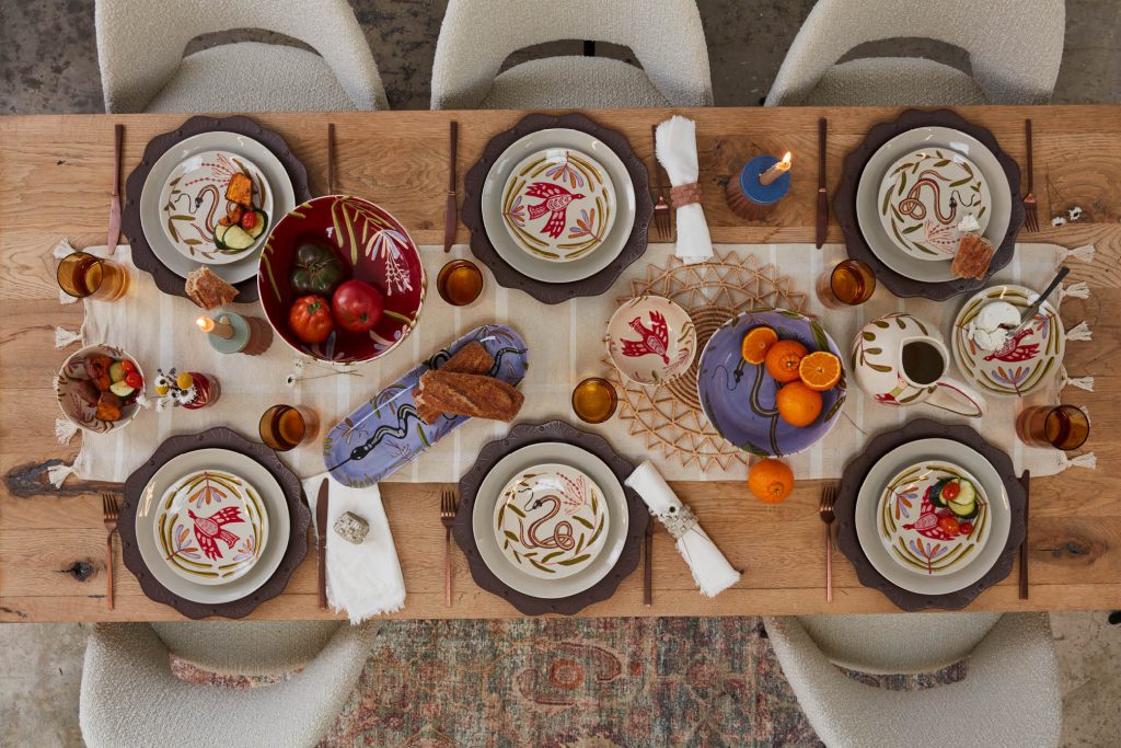 A kitchen table adorned with elegant tabletop decor. The table is made of polished wood, with a smooth surface reflecting the soft ambient light. In the center, there is a tall vase filled with vibrant flowers, adding a pop of color to the scene.