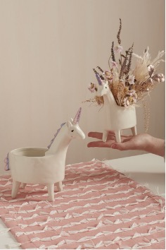 Lolly Unicorn Planter held by an outstreched hand.