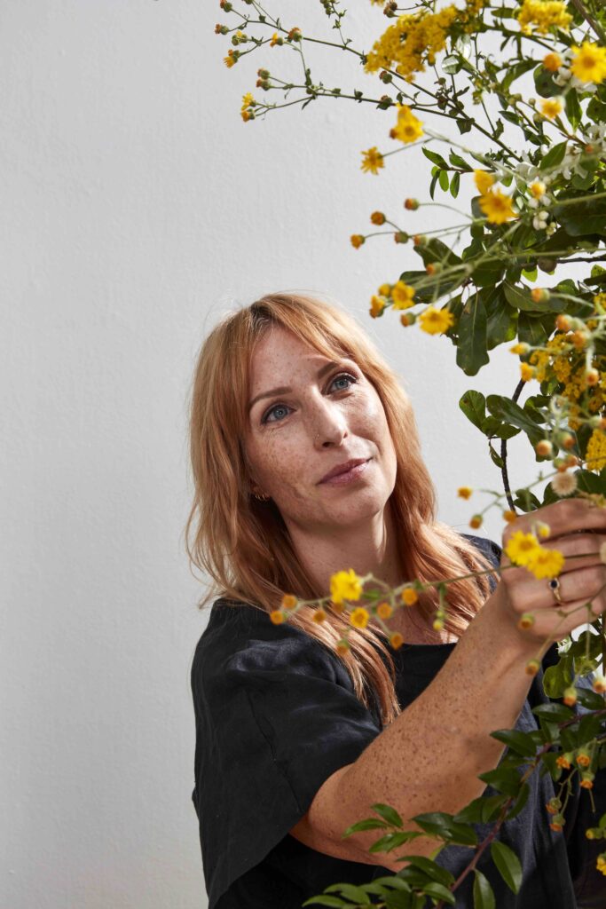 Image of Sue McLeary, Passionflower Sue, surrounded by yellow flowers. 