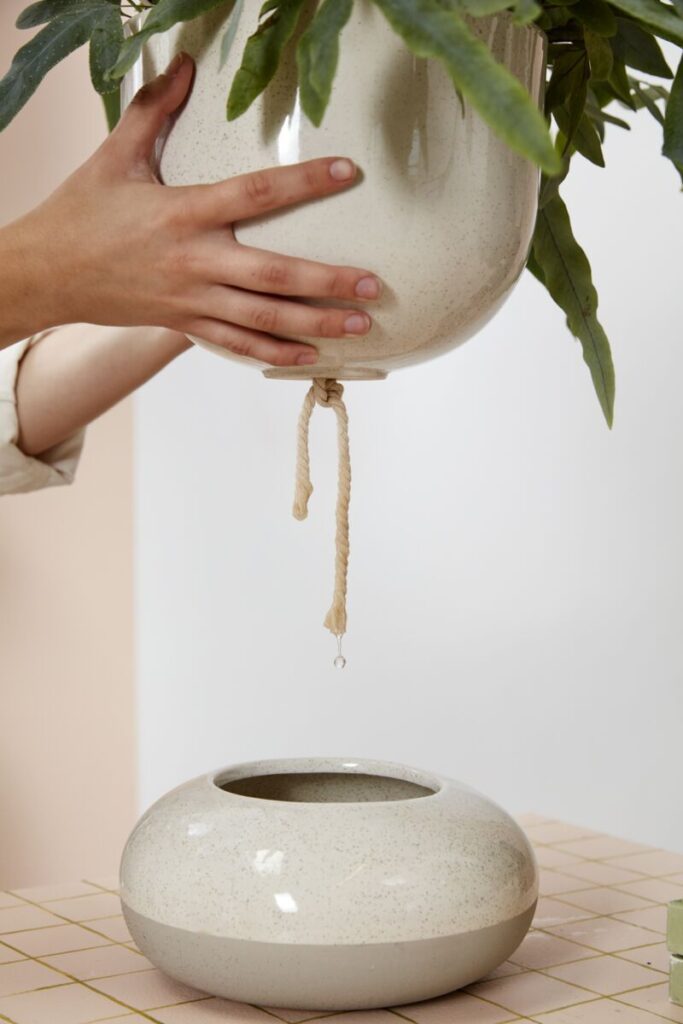 Hands interacting with the self-watering Tartu Pot with Saucer from Accent Decor.