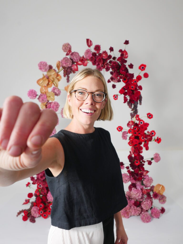 Image of Lys Lytle of Flowering Minds Education surrounded by arch decor for weddings.