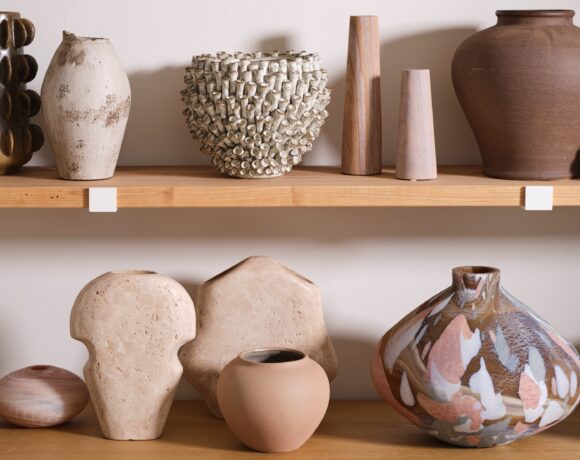 A variety of wholesale home decor vases and planters styled on wooden shelves.