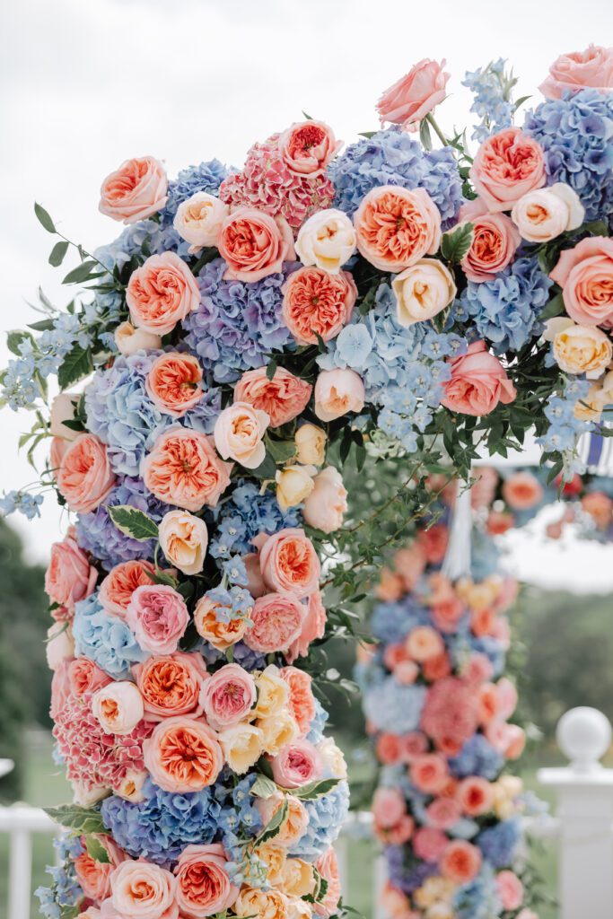 A close-up shot of blue, pink and peach florals within arch decor wedding.
