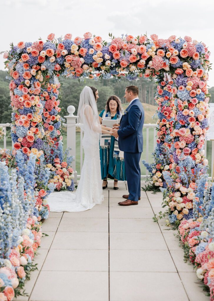 Jackie Levine, of Central Square Florist, and her husband during their wedding ceremony near arch decor wedding.