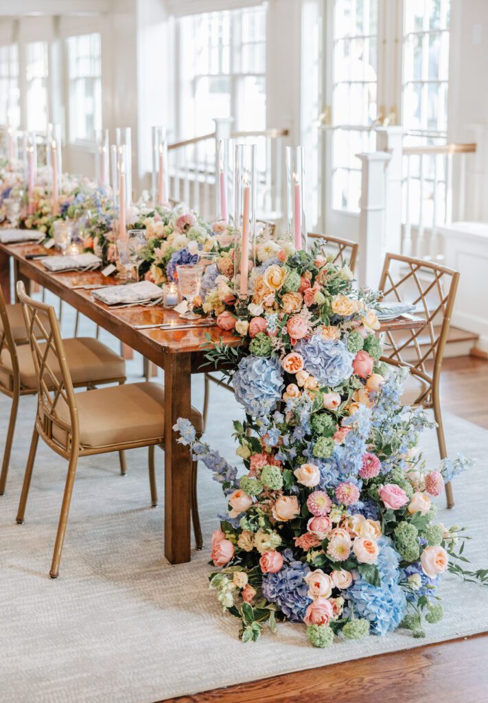A beautiful wedding reception table featuring sprawling florals and candles.