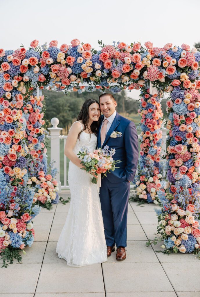 Jackie Levine, of Central Square Florist, and her husband posing near arch decor wedding.