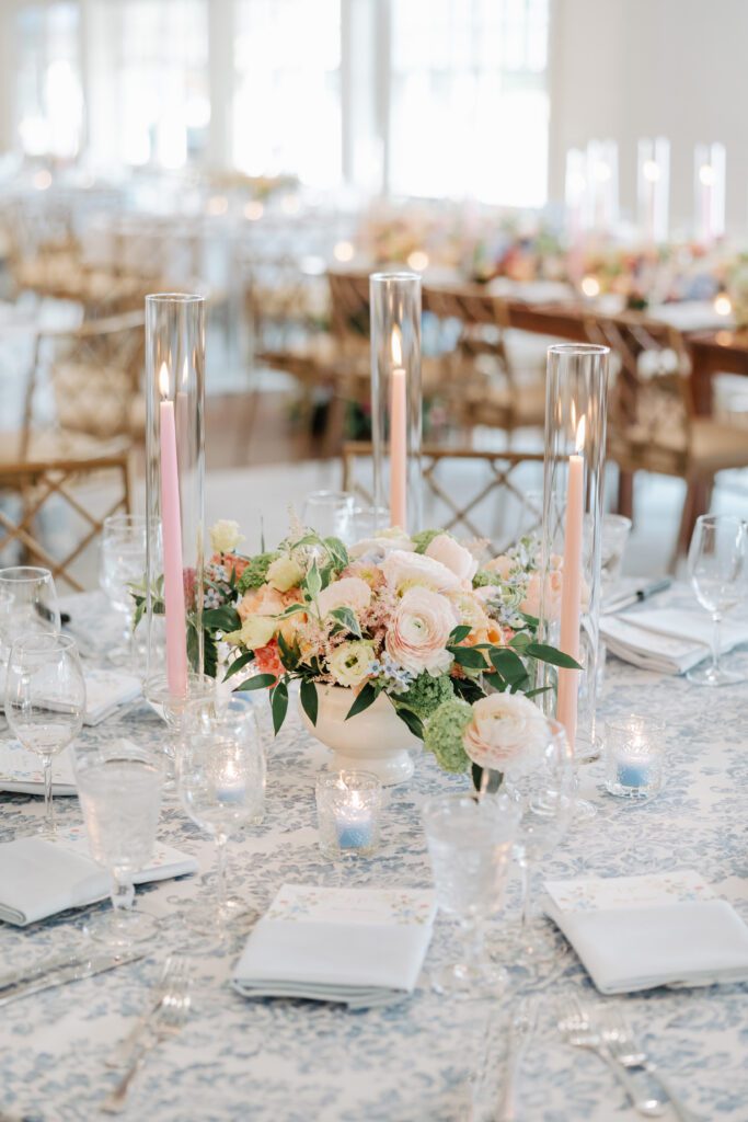 A close-up shot of a beautiful wedding reception centerpiece featuring peach and blue colored flowers and candlesticks.