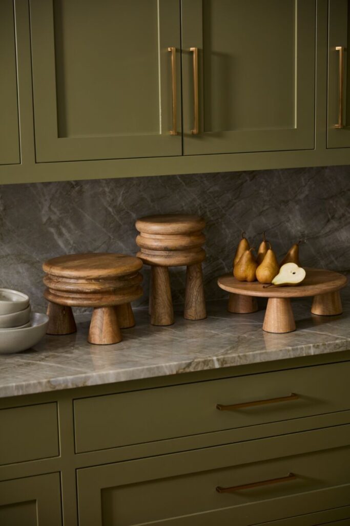 The Accent Decor Atticus Stands set atop a kitchen counter alongside fresh pears and bowls. 
