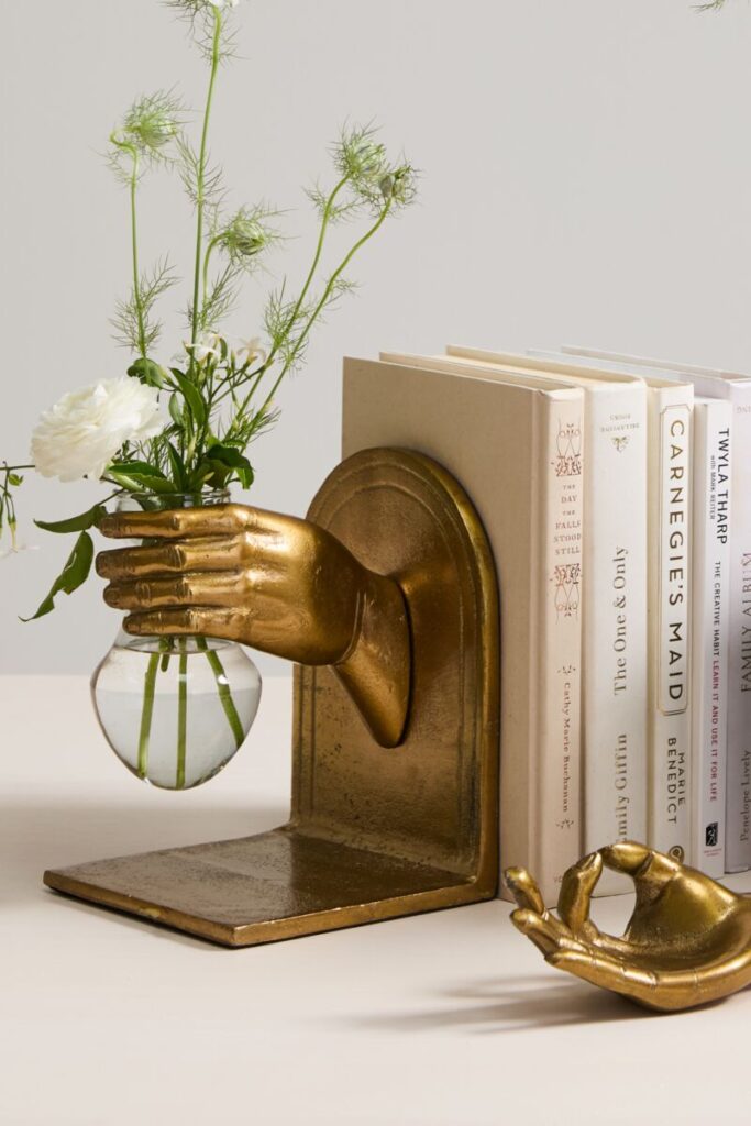 Accent Decor's Handheld Bookends adorned with a small bouquet of flowers propped against a small collection of books.