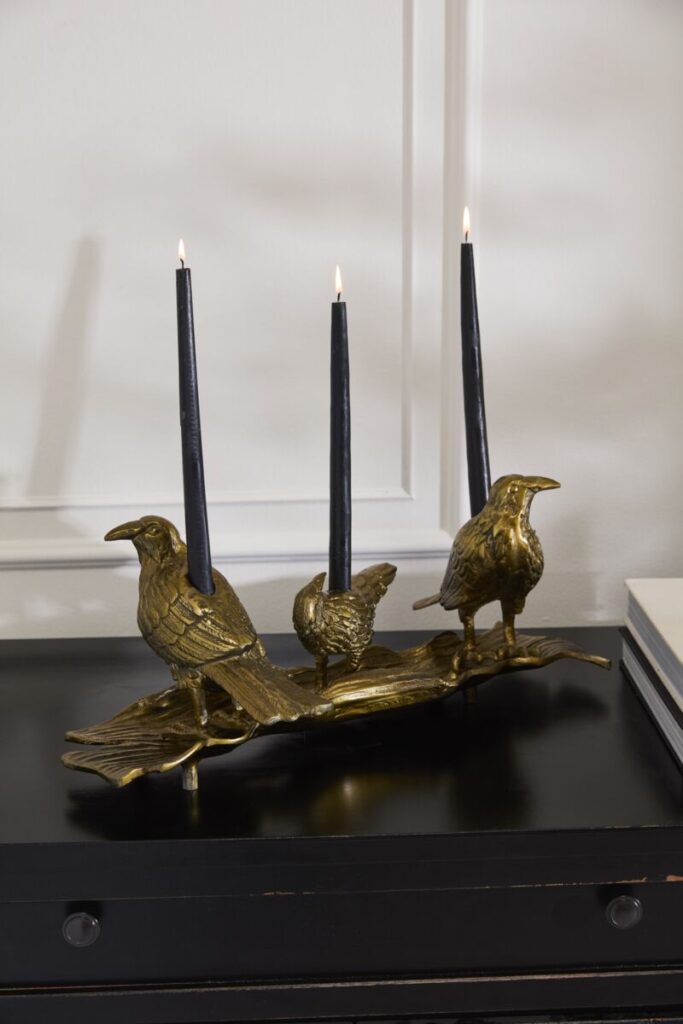 Accent Decor's Three Ravens Candleholder atop a table with three black candles. 