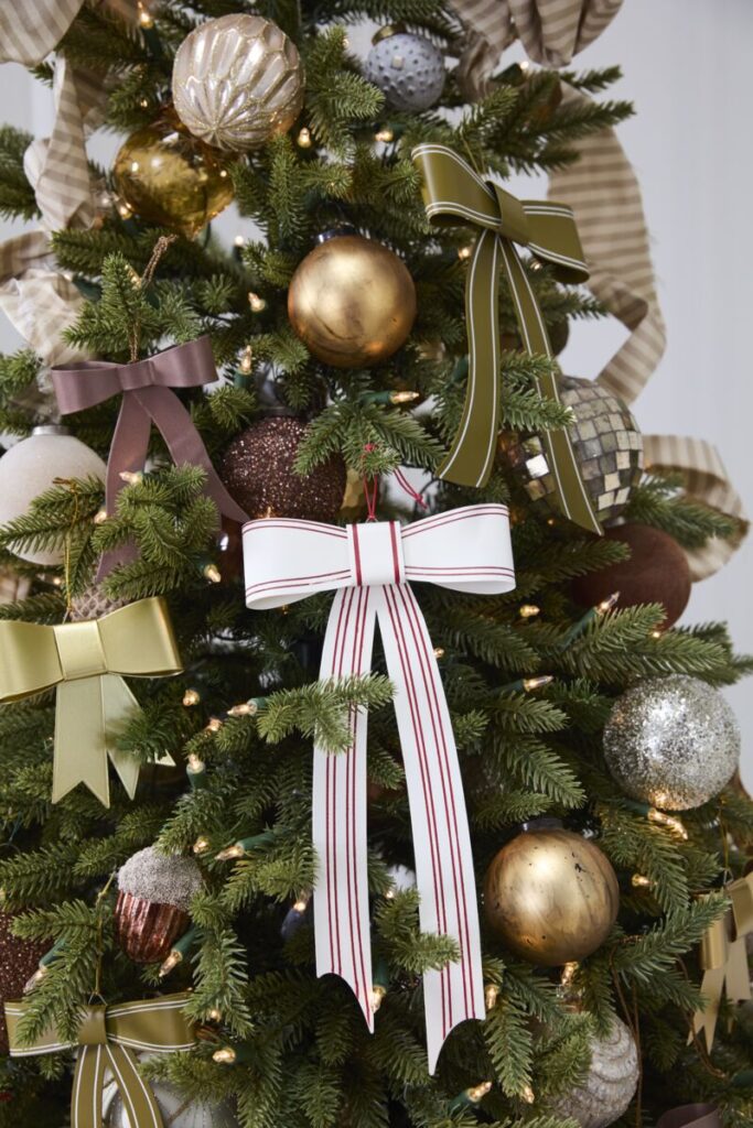 A Christmas tree adorned with shimmering gold & silver ornaments, accented by Accent Decor’s red-ribboned Candace Ornaments.