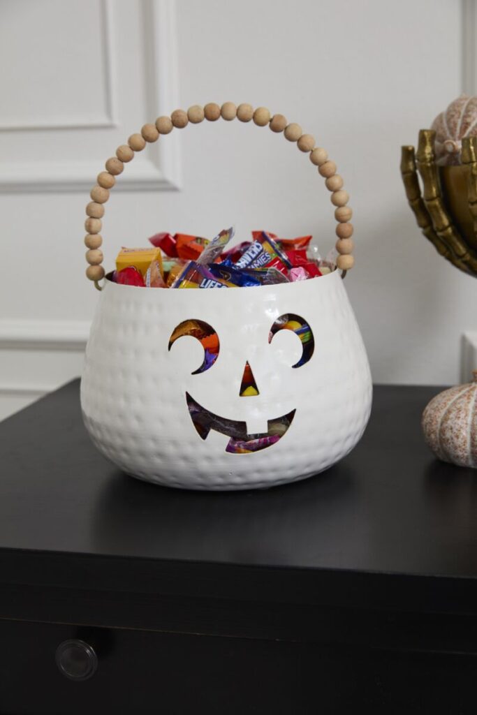 Accent Decor's Charming Pumpkin Basket on a tabletop, filled with colorful Halloween candy.