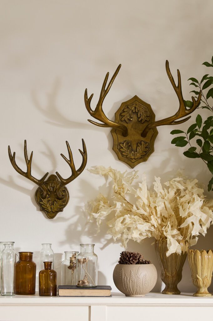 Accent Decor's Oakdale Antler Wall Mount styled on a white wall near an assortment of wholesale decor vases. 