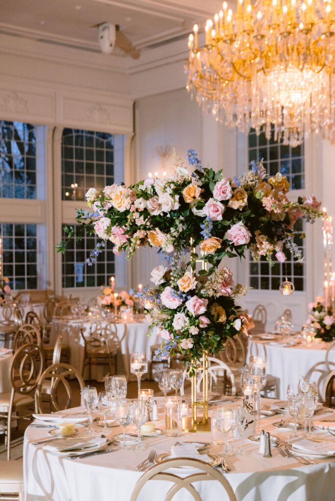 A beautifully decorated wedding reception tablescape ft. white linens, glassware, florals and greenery.