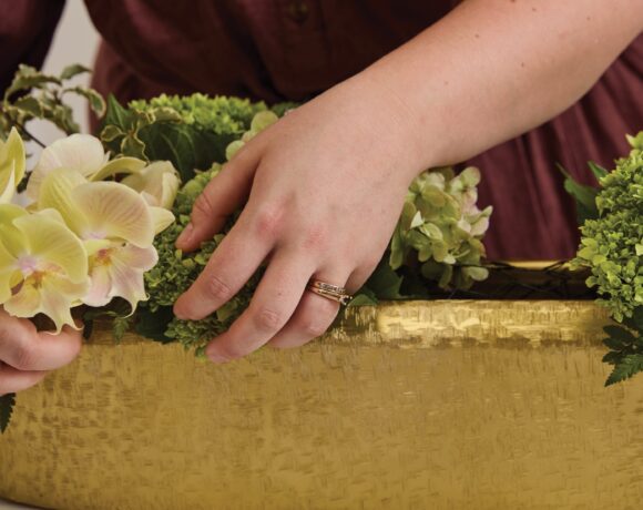 Image of hands arranging florals into the Blaze Trough, a decorative trough, offered by wholesale decor supplier, Accent Decor.