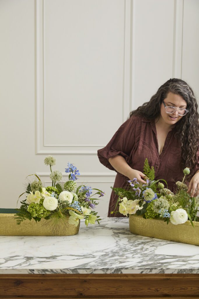 Image of a woman arranging florals into the Blaze Trough, a decorative trough, offered by wholesale decor supplier, Accent Decor.