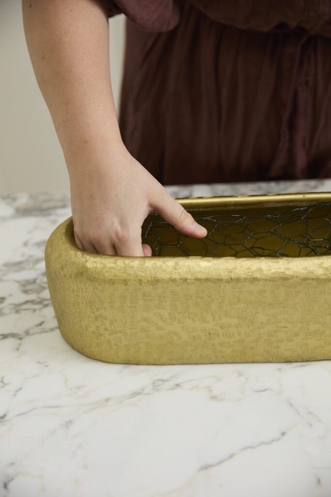 Image of hands manipulating chicken wire into the Blaze Trough, a decorative trough, offered by wholesale decor supplier, Accent Decor.