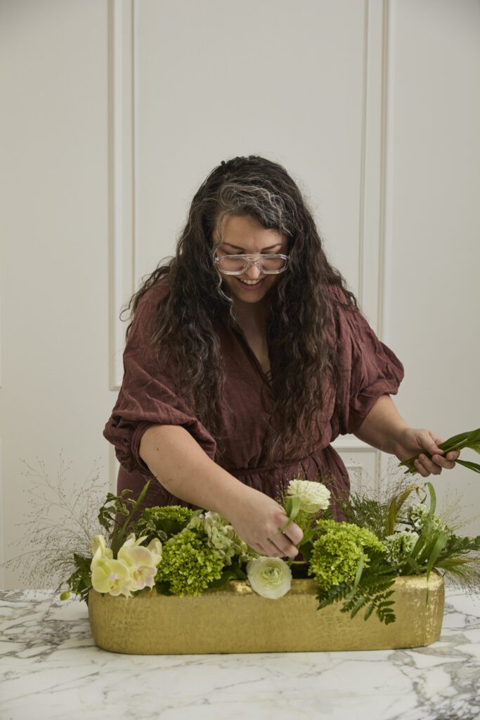 Image of a woman arranging florals into the Blaze Trough, a decorative trough, offered by wholesale decor supplier, Accent Decor.