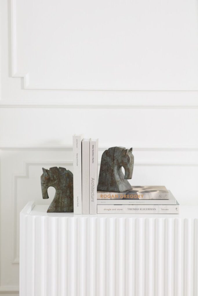 A stack of books flanked b y horse-inspired bookends inaged patina of blue & dark grey hues.