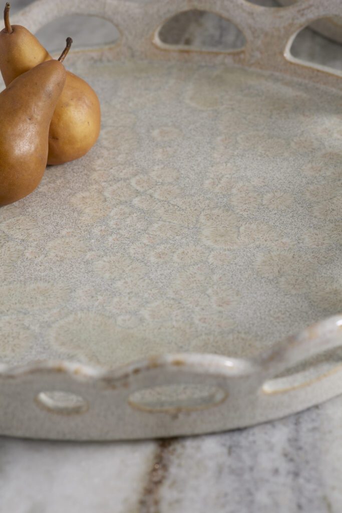 A scalloped tray atop a countertop with pears and cheese.