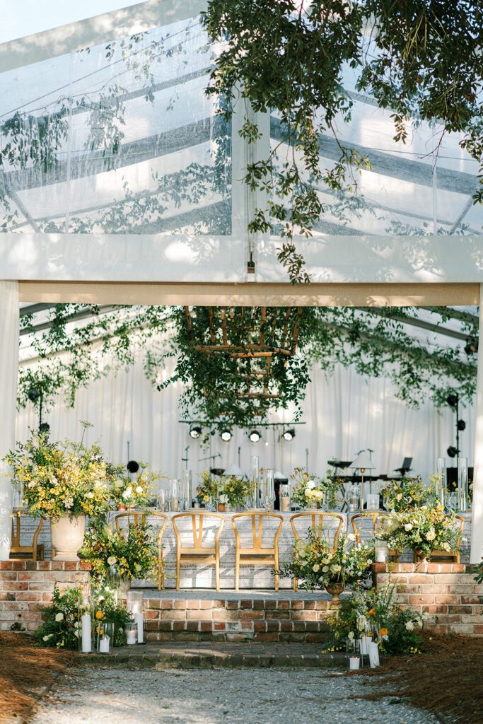 A dramatic outdoor event space outfitted with a styled tabletop featuring beautiful, lush florals and greenery.