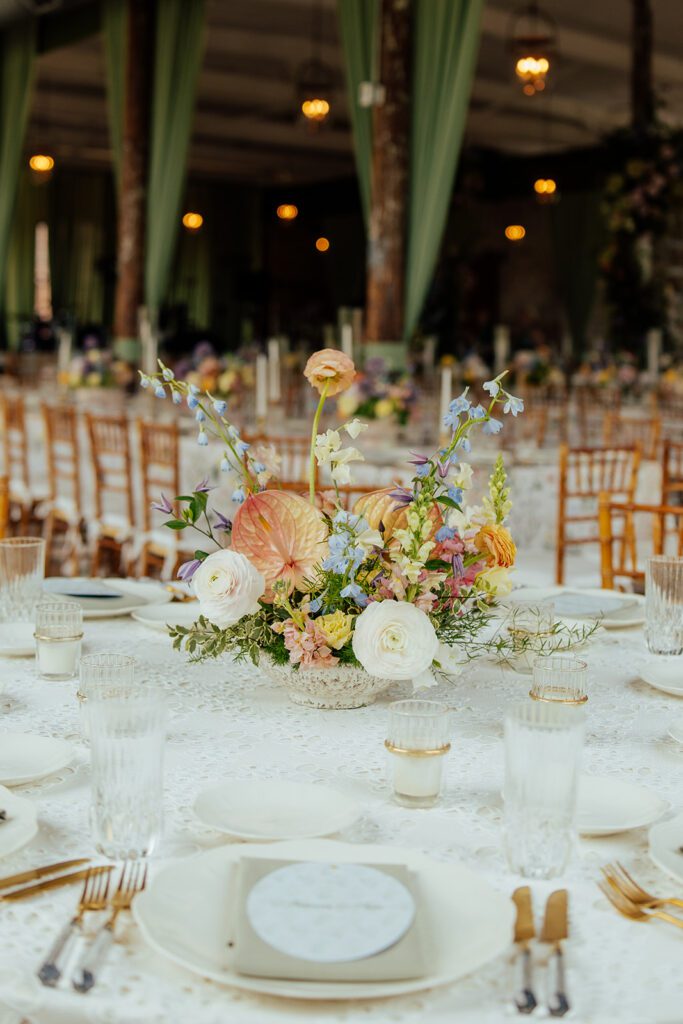 An event tabletop styled with fresh, colorful flowers and wholesale event decor including votives and flatware.