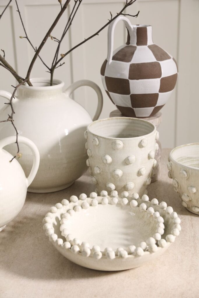 Assortment of white and taupe wholesale home decor accents atop a table, stylishly arranged.