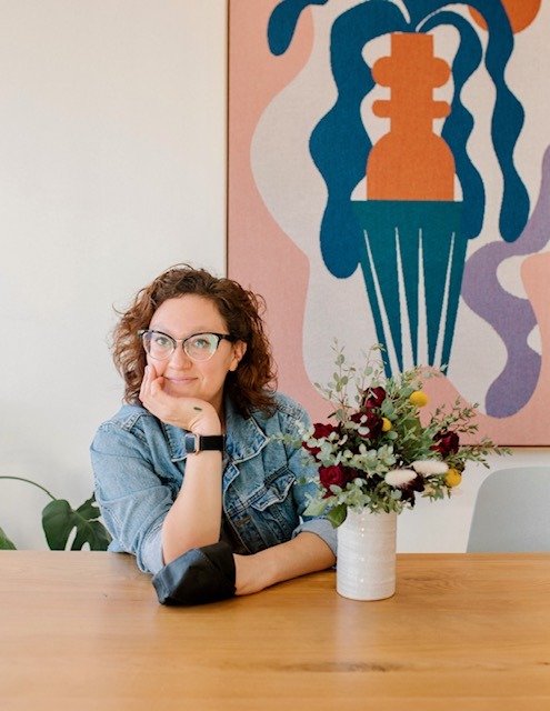 A floral designer beside a bouquet of fresh florals.