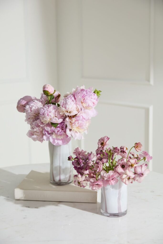 White and light pink striped vases filled with striking and lush florals.