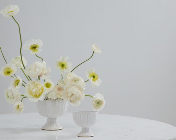 White floral compotes atop a table with styled florals.