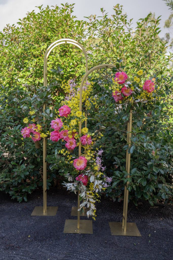 Large arch wedding decor, the Melora Arch, styled with lush flowers in pink, yellow and green.
