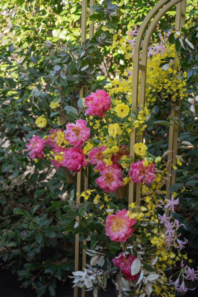 Large arch wedding decor, the Melora Arch, styled with lush flowers in pink, yellow and green.