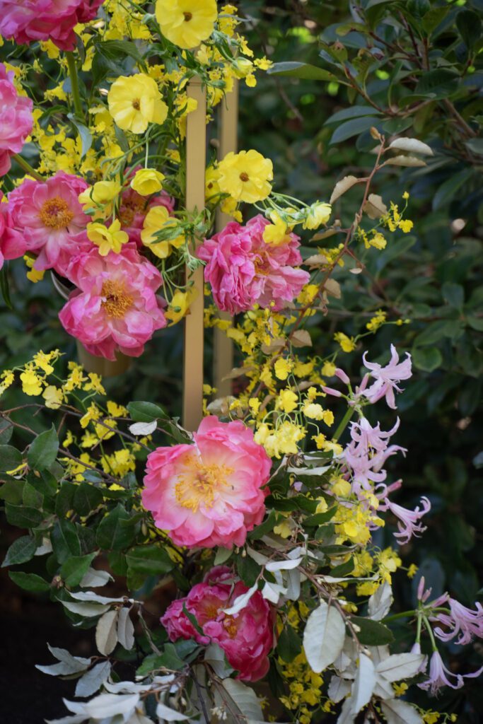 Large arch wedding decor, the Melora Arch, styled with lush flowers in pink, yellow and green.