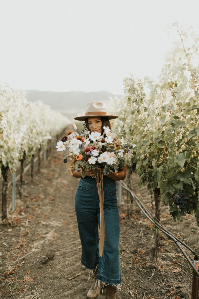 Image of woman in field with a large flower bouquet.
