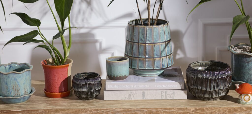 A tabletop featuring an assortment of colorful and glazed pots and planters